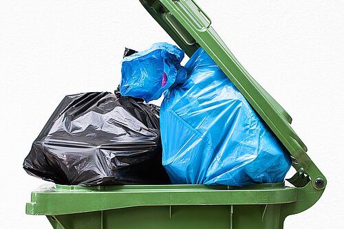 A wheelie bin overflowing with rubbish.