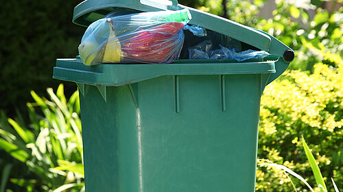 A wheelie bin overflowing with rubbish.